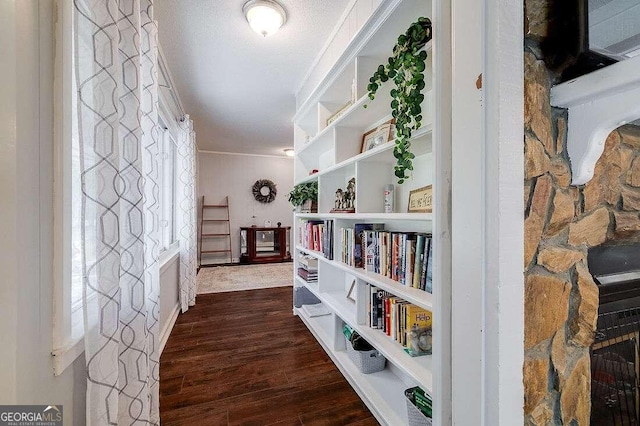 corridor with a textured ceiling, dark hardwood / wood-style flooring, and ornamental molding