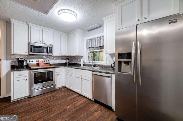 kitchen with appliances with stainless steel finishes, dark hardwood / wood-style flooring, and white cabinetry