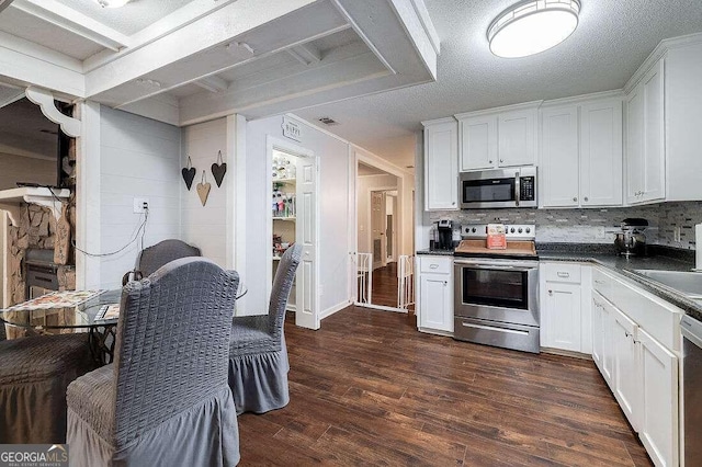 kitchen with backsplash, dark wood-type flooring, white cabinets, a textured ceiling, and appliances with stainless steel finishes