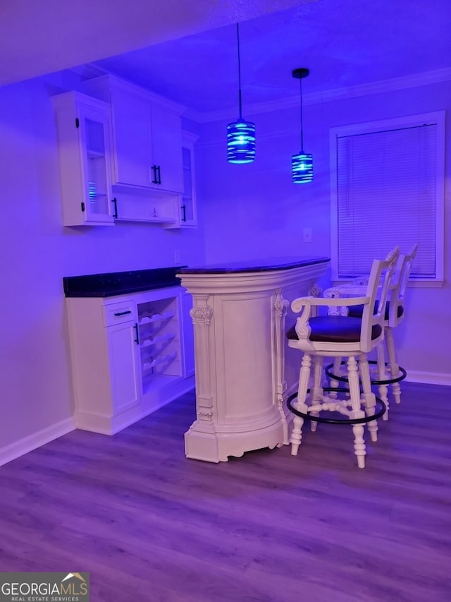 bar with crown molding, white cabinets, pendant lighting, and hardwood / wood-style flooring