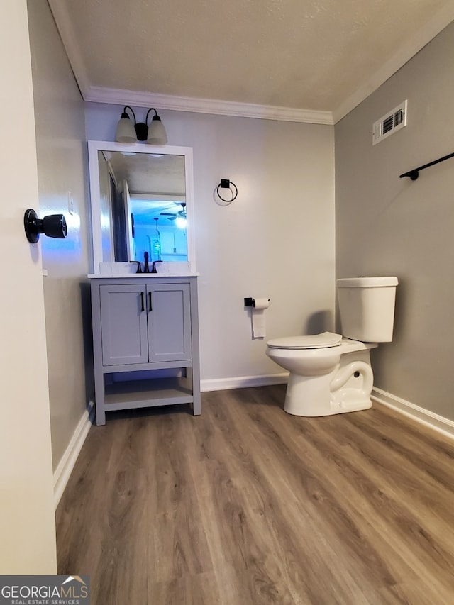 bathroom with toilet, hardwood / wood-style floors, vanity, and ornamental molding