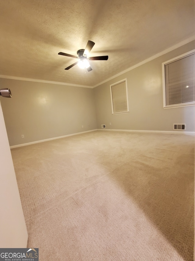 carpeted spare room with crown molding, ceiling fan, and a textured ceiling