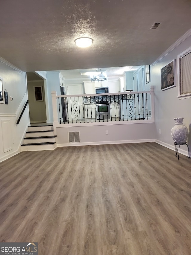 interior space featuring hardwood / wood-style floors, crown molding, and a textured ceiling