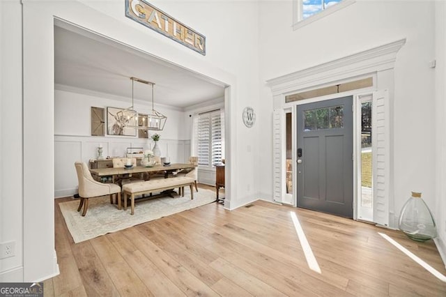 foyer with light wood-type flooring and ornamental molding