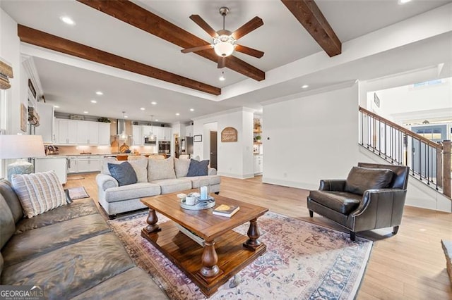 living room featuring beam ceiling, light hardwood / wood-style flooring, and ceiling fan