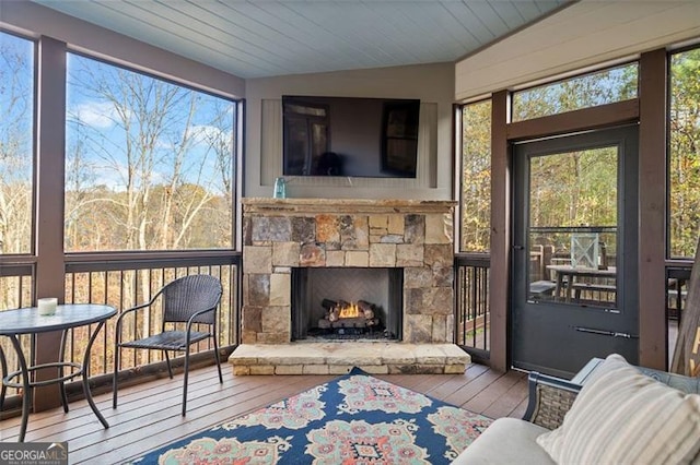 sunroom with a stone fireplace, wooden ceiling, and vaulted ceiling