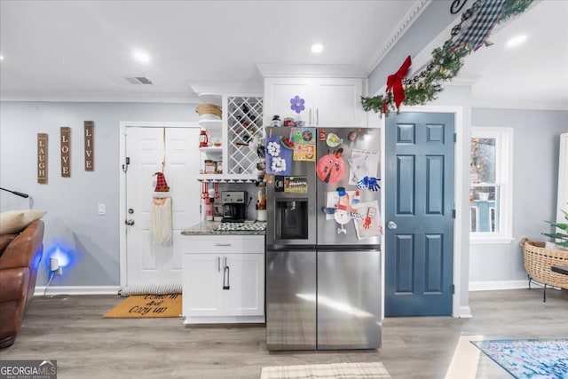 kitchen with white cabinets, stainless steel fridge with ice dispenser, light hardwood / wood-style flooring, and crown molding