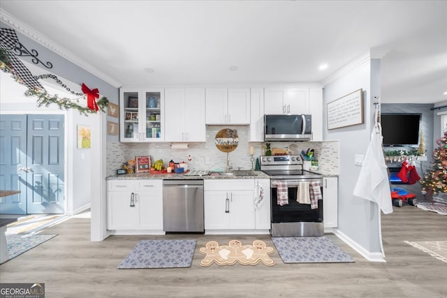 kitchen featuring white cabinets, crown molding, decorative backsplash, appliances with stainless steel finishes, and light hardwood / wood-style floors