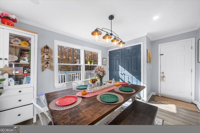 dining area with hardwood / wood-style floors, crown molding, and an inviting chandelier