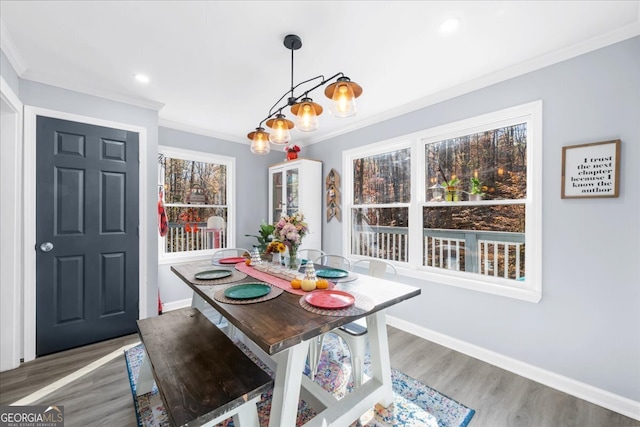 dining area featuring hardwood / wood-style floors, crown molding, and a notable chandelier