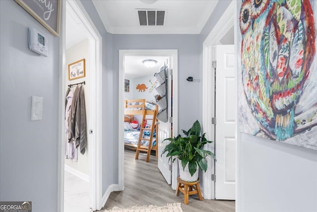 corridor with light hardwood / wood-style floors and crown molding