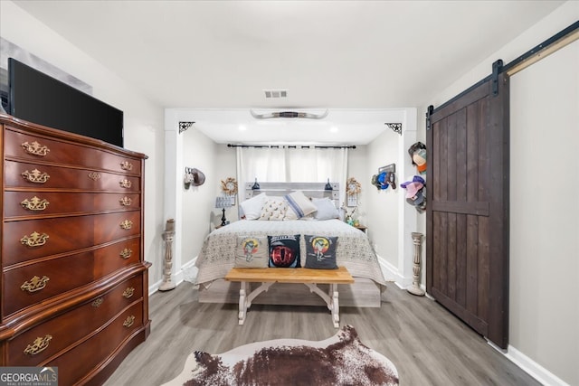 bedroom featuring a barn door and light wood-type flooring