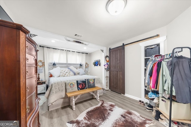 bedroom featuring a barn door and light wood-type flooring