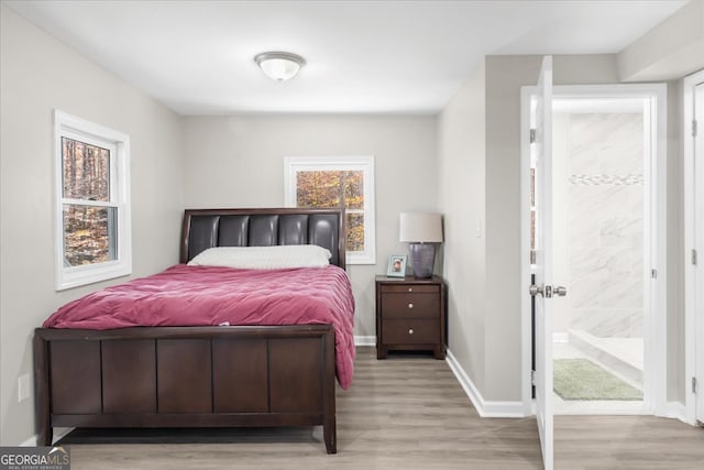 bedroom featuring light wood-type flooring and ensuite bath