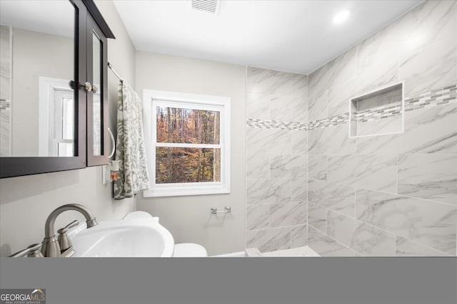 bathroom with a tile shower and sink