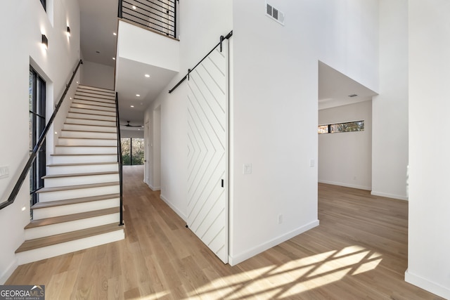 stairs with a towering ceiling and wood-type flooring