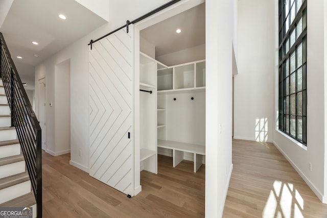 mudroom with a barn door and light hardwood / wood-style floors