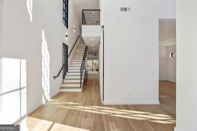 staircase with hardwood / wood-style flooring and a high ceiling