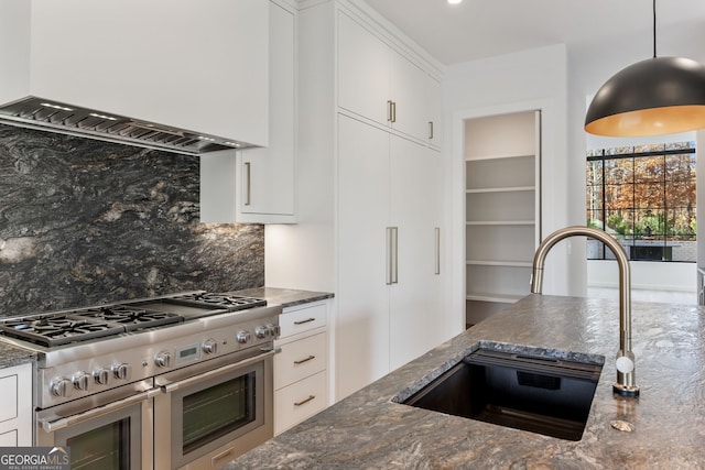 kitchen with white cabinets, decorative backsplash, and range with two ovens