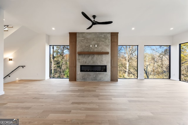 unfurnished living room featuring a fireplace, light hardwood / wood-style flooring, and ceiling fan