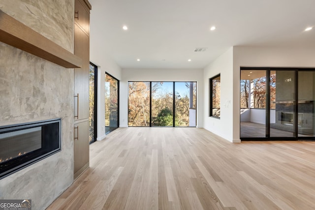 unfurnished living room with a large fireplace and light hardwood / wood-style floors