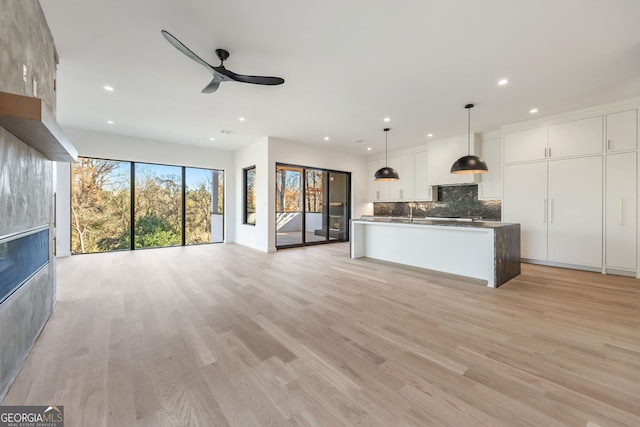 unfurnished living room with ceiling fan, light wood-type flooring, and sink