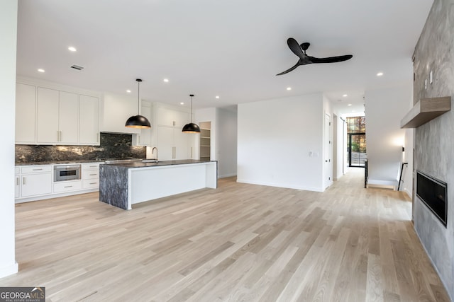 kitchen with pendant lighting, white cabinetry, stainless steel appliances, and light hardwood / wood-style flooring