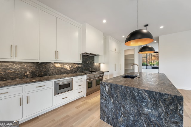 kitchen featuring white cabinetry, sink, stainless steel appliances, a spacious island, and light hardwood / wood-style floors