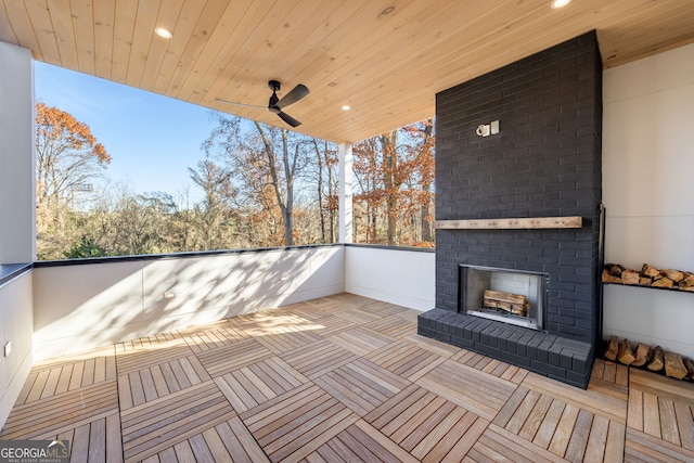 wooden deck featuring an outdoor brick fireplace and ceiling fan