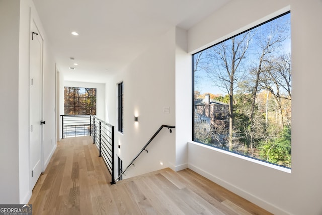 hallway with light hardwood / wood-style flooring and a wealth of natural light