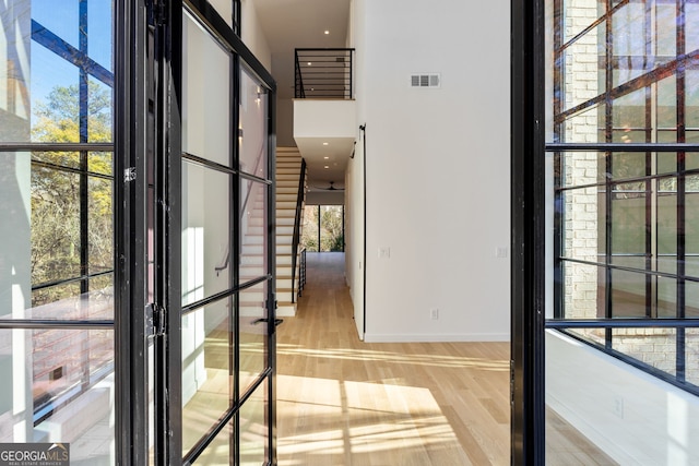 interior space featuring a towering ceiling and wood-type flooring