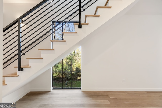 staircase featuring wood-type flooring and a high ceiling