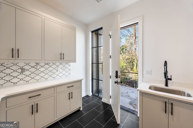 interior space with backsplash, dark tile patterned floors, and sink