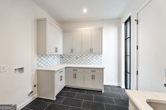 clothes washing area with dark tile patterned flooring, electric dryer hookup, cabinets, and washer hookup