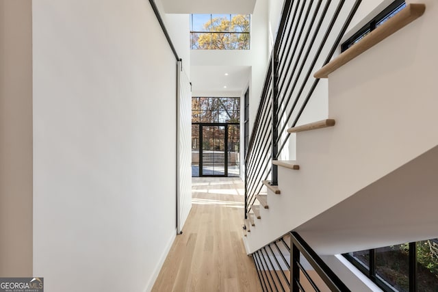 stairs featuring a towering ceiling and wood-type flooring