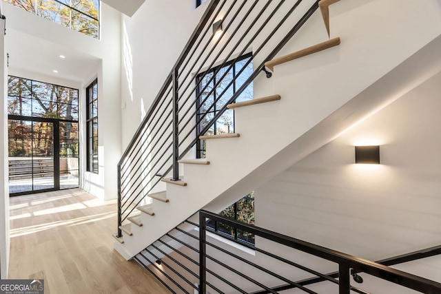 staircase featuring hardwood / wood-style flooring, a towering ceiling, and french doors