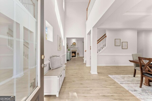 foyer entrance featuring a towering ceiling and light wood-type flooring