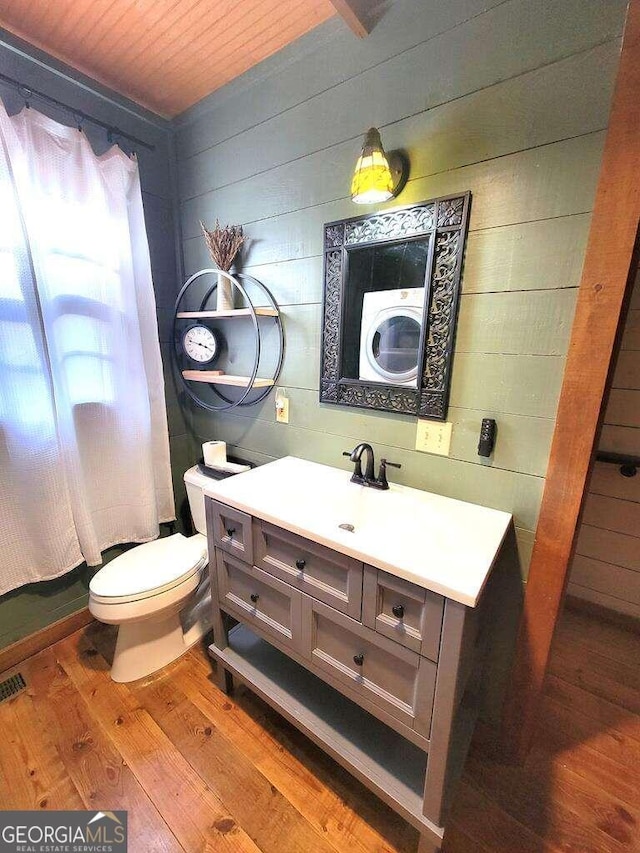 bathroom featuring washer / clothes dryer, hardwood / wood-style floors, toilet, vanity, and wood ceiling