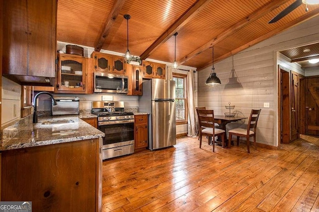 kitchen featuring sink, light hardwood / wood-style flooring, lofted ceiling with beams, pendant lighting, and appliances with stainless steel finishes