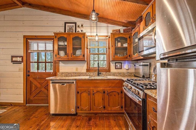 kitchen featuring light stone counters, pendant lighting, stainless steel appliances, and vaulted ceiling