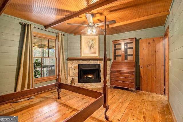 sitting room featuring a stone fireplace, beamed ceiling, wood ceiling, and light wood-type flooring