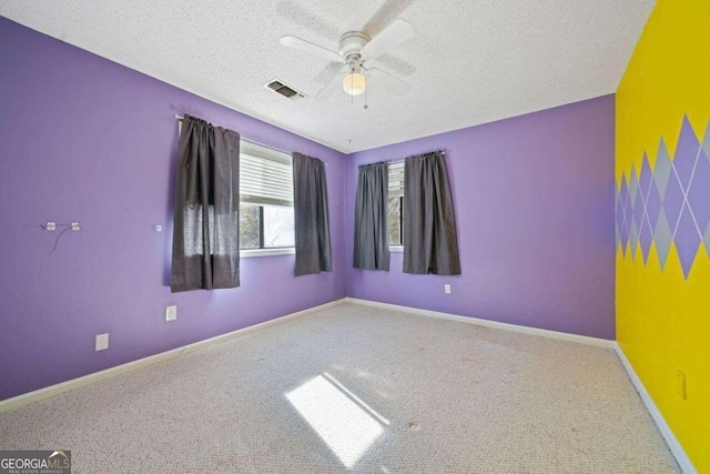 carpeted spare room with a textured ceiling and ceiling fan