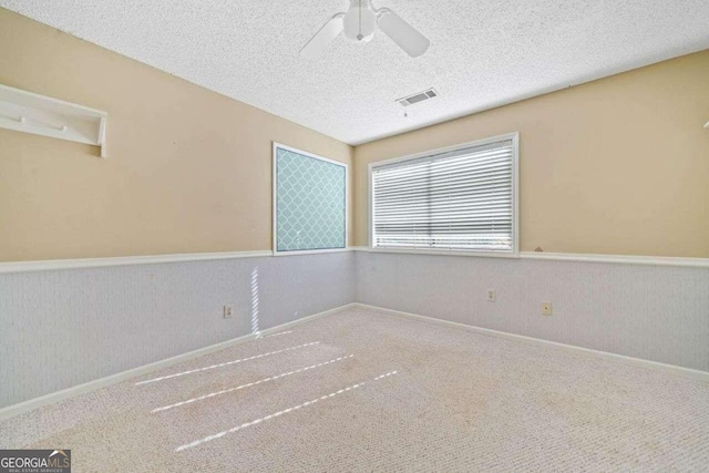 empty room featuring carpet flooring, ceiling fan, and a textured ceiling