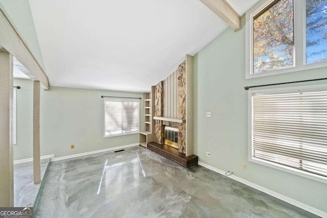 unfurnished living room featuring a stone fireplace, concrete floors, and vaulted ceiling with beams