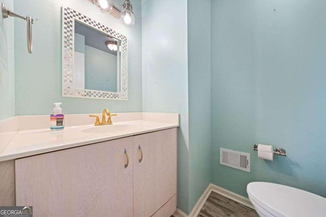 bathroom featuring toilet, vanity, and hardwood / wood-style flooring