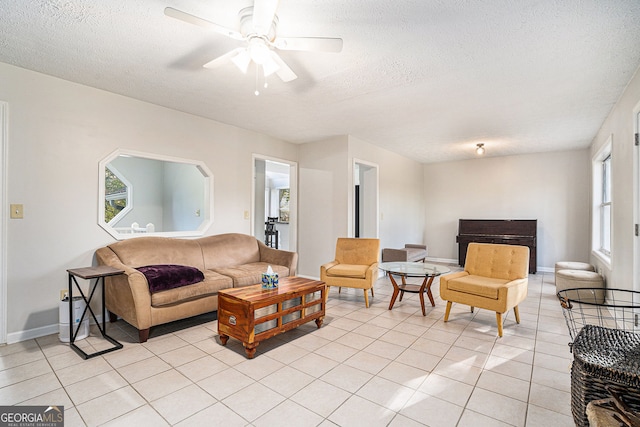 living room featuring ceiling fan, light tile patterned floors, and a textured ceiling