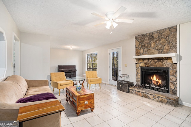 tiled living room with a fireplace, ceiling fan, and a textured ceiling