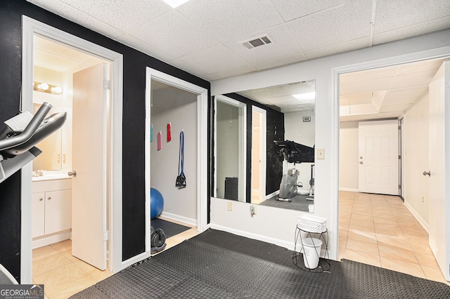 hallway featuring tile patterned floors and a drop ceiling