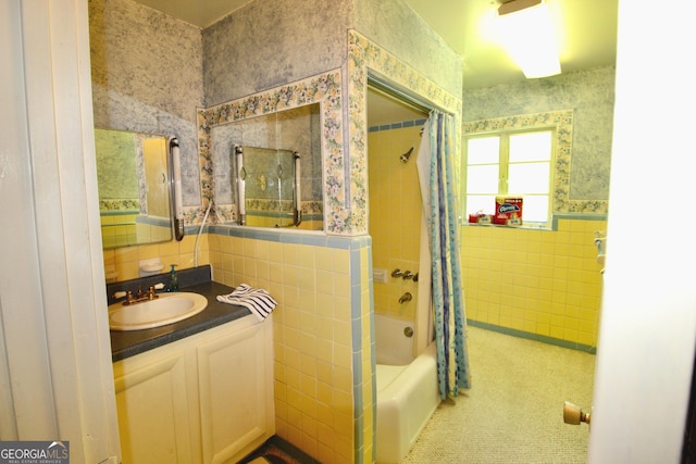 bathroom with shower / bath combo, vanity, and tile walls