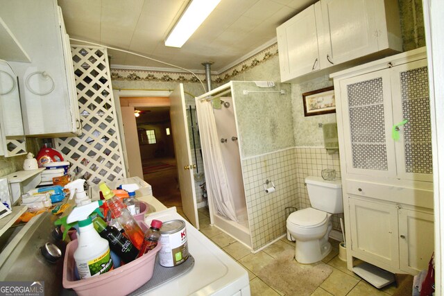 bathroom with toilet, tile patterned flooring, tile walls, and walk in shower